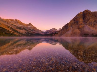 Bow Gölü, Alberta, Kanada. Gün doğumunda dağ manzarası. Suyun yüzeyindeki yansımalar. Vadideki güneş ışınları. Arkaplan, duvar kağıdı, kartpostallar.