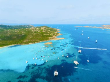 Denizin ortasındaki ada. Yatların, teknelerin ve adanın insansız hava aracı görüntüsü. Tatil yapan insanlar. Kuzeydoğu Sardunya, Maddalena Takımadası. Tatil ve tatiller. Deniz yolculuğu için yaz zamanı.