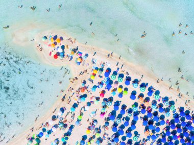 Yaz tatili ve dinlenme. Plaj, insanlar ve şemsiyeler. Kumsaldaki İHA 'nın ve gök mavisi denizin üst görüntüsü. İHA 'dan sahile bak. Arkaplan, duvar kağıdı, kartpostallar.