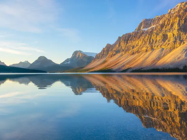Bow Gölü, Alberta, Kanada. Gün doğumunda dağ manzarası. Suyun yüzeyindeki yansımalar. Vadideki güneş ışınları. Arkaplan, duvar kağıdı, kartpostallar.