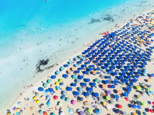 Yaz tatili ve dinlenme. Plaj, insanlar ve şemsiyeler. Kumsaldaki İHA 'nın ve gök mavisi denizin üst görüntüsü. İHA 'dan sahile bak. Arkaplan, duvar kağıdı, kartpostallar.