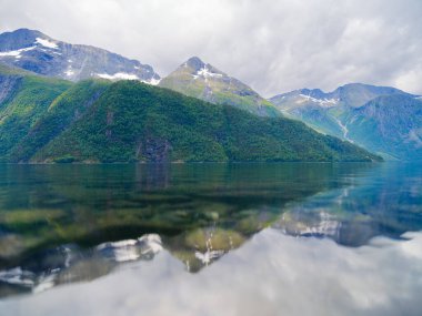 Norveç. Fiyortlarda doğa. Yüksek dağlar ve yansımalar. Kayaların üzerindeki bulutlar. Norveç 'te yaz tatili ve seyahat. Arkaplan, duvar kağıdı, kartpostallar.