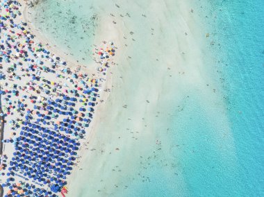 Yaz tatili ve dinlenme. Plaj, insanlar ve şemsiyeler. Kumsaldaki İHA 'nın ve gök mavisi denizin üst görüntüsü. İHA 'dan sahile bak. Arkaplan, duvar kağıdı, kartpostallar.