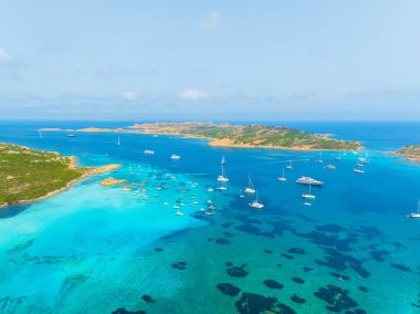 Denizin ortasındaki ada. Yatların, teknelerin ve adanın insansız hava aracı görüntüsü. Tatil yapan insanlar. Kuzey-Doğu Sardunya, Maddalena Takımadası. Tatil ve tatiller. Arkaplan, duvar kağıdı, kartpostal.