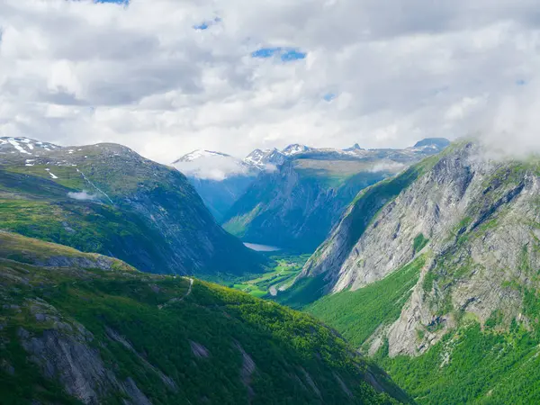 Norveç fiyordu. Yüksek dağlar ve orman. Kayaların üzerindeki bulutlar. Norveç 'te yaz tatili ve seyahat. Duvar kağıdı, kartpostal, geçmiş. Dağ yürüyüşü, seyahat ve tatil yeri. 