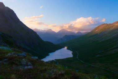 Norveç 'te doğa. Vahşi Norveç 'in panoramik manzarası. Kayaların ve dağların arasında nehir ve göl. Gün doğumunda parlak güneş ışığı. Tatil ve seyahatler Kuzey 'de. 