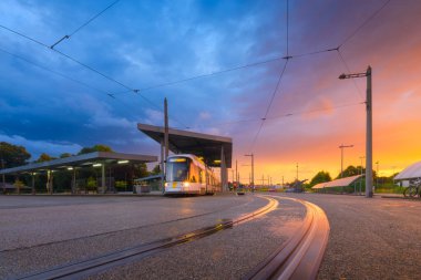 Tramvay durağı. Gün batımında toplu taşıma ve gökyüzü. Mimari ve altyapısal görüş. Kartpostallar, duvar kağıtları ve arka planlar için fotoğraf.