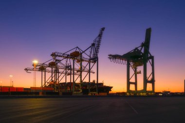 Denizci ticari terminali. Malların konteynırlarda taşınması. Kargo teslimatı için deniz taşımacılığı. Endüstri. Gün batımında vinçlerin siluetleri.