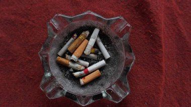 Küllükte sigara izmaritleri, kırmızı halı, dağınık küller, sigara karşıtı kampanya fotoğrafı konsepti Wonosobo Endonezya 18 Haziran 2023