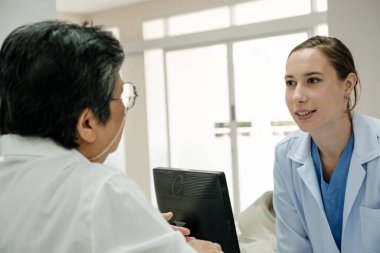 Young female doctor health examination to old female patient sitting on wheelchair.