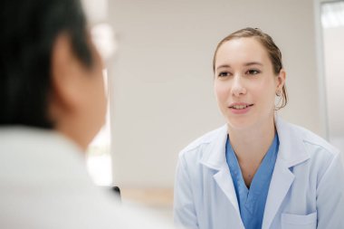 Young female doctor health examination to old female patient sitting on wheelchair.