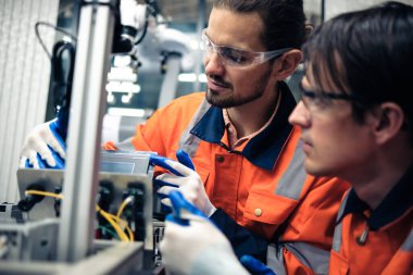 Robot makine atölyesinde robot kol makinesi eğitimi alan çok ırklı taşikardi mühendisi..