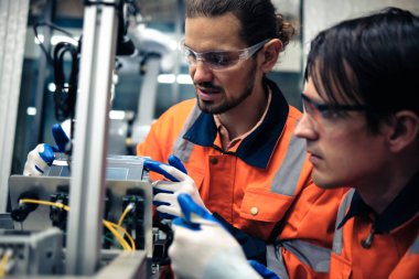Robot makine atölyesinde robot kol makinesi eğitimi alan çok ırklı taşikardi mühendisi..