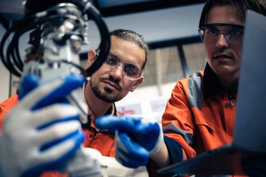 Robot makine atölyesinde robot kol makinesi eğitimi alan çok ırklı taşikardi mühendisi..