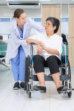 Young female doctor health examination to old female patient sitting on wheelchair.
