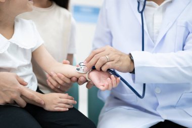 Doktor genç hastanın elini tuttu ve annesi gülümsedi ve onu cesaretlendirdi..