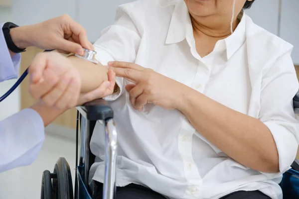 stock image Young female doctor health examination to old female patient sitting on wheelchair.