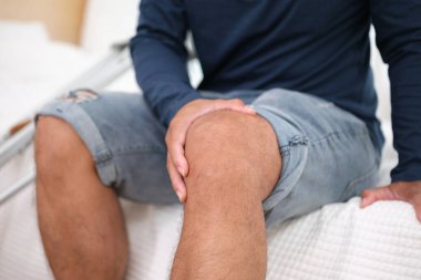 Asyalı adam koltuk değneği kullanıyor çünkü evde dizlerinin üstüne çökmüş durumda..