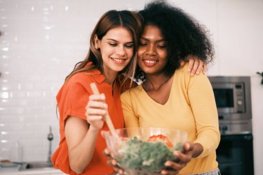 Kitche 'de salata pişiren çok ırklı lezbiyen çift.