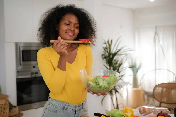 stock image Multiracial young woman cooking salad at home.