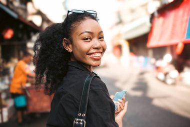 Asyalı kadın şehir merkezinde gezmekten hoşlanıyor ve fotoğraf çekiyor ve sosyal medyada canlı olarak cep telefonu kullanıyor ve sokak yemekleri tadıyor..
