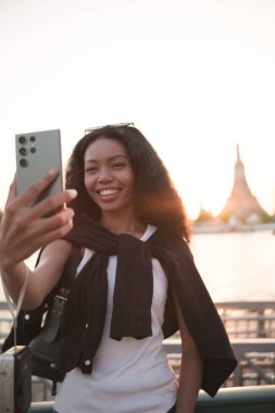 Asyalı kadın şehir merkezinde gezmekten hoşlanıyor ve fotoğraf çekiyor ve sosyal medyada canlı olarak cep telefonu kullanıyor ve sokak yemekleri tadıyor..