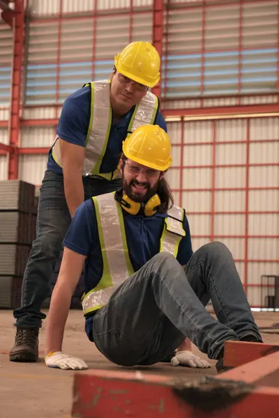 Engineers helping colleague has accident at work in the factory.