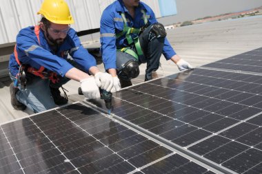 Mühendisler ya da işçiler fabrikanın çatısına güneş pili kurup teftiş ediyorlar..
