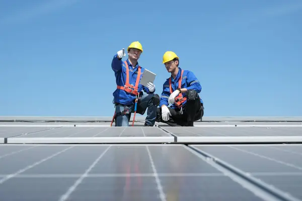 Engineers or workers install and inspect solar cells on the roof of the factory.