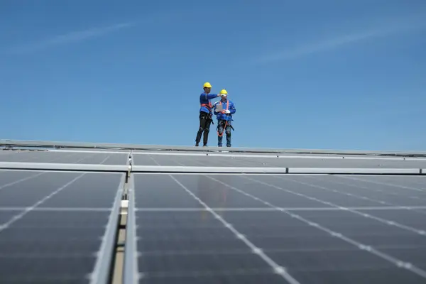 Engineers or workers install and inspect solar cells on the roof of the factory.