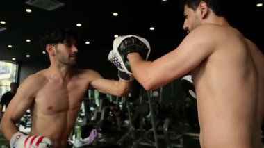 Genç adam boks antrenörüyle spor yapıyor..