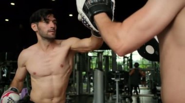 Genç adam boks antrenörüyle spor yapıyor..