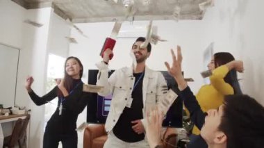 İş arkadaşı para tabancası kullanıyor ve işini başarıyla yapmadan önce ofiste mutlu bir şekilde dans ediyor..