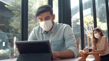 Müşteri kahve dükkanında çalışırken maske takıyor. 