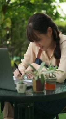 Genç Asyalı kadın kaktüs hakkında bilgi topluyor ve kaktüs hakkında bilgi depolamak için dizüstü bilgisayar kullanıyor. 