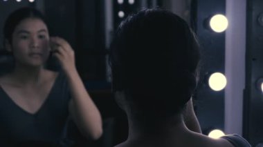 Aynanın önünde makyaj yapan genç bir kadın.