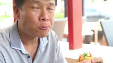 Hamburger yiyen Asya 'lı adama yaklaş.