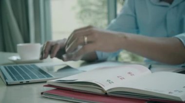 Ofisteki masada kasklı ve güvenlik kıyafetli bir adam dizüstü bilgisayarla çalışıyor.