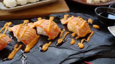 Elinizi kırmızı çubuklarla kapayın ve siyah tabakta somon balığı alın.