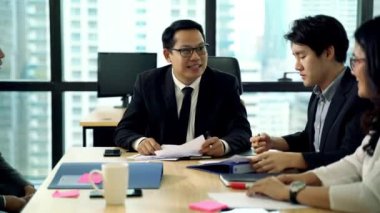 İş adamlarından oluşan bir ekip çalışmalarını tartışıyor ve toplantı odasında el ele tutuşuyorlar.