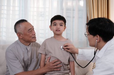 Doktor çocuğu muayene ediyor. Büyükbabası ve babasıyla birlikte geliyor..