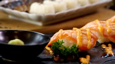 Japon yemeği, somon balığı, uskumru, tatlı soslu Japon pilavı ve siyah arka planda somon salatası..