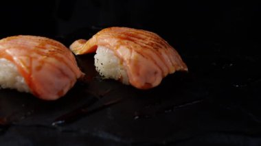 Siyah arka planda Japon yemek somon suşisine yakın çekim.