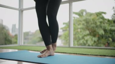 Sabahları evde yoga egzersizi yapan genç bir kadın.