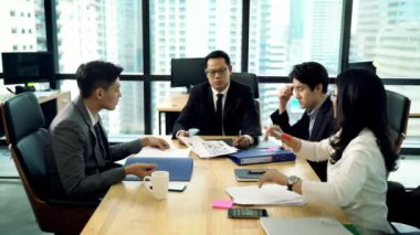 İş adamlarından oluşan bir ekip çalışmalarını tartışıyor ve toplantı odasında el ele tutuşuyorlar.