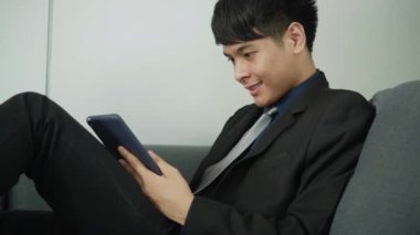 İş adamı kanepede rahatlıyor ve tablet kullanıyor. 