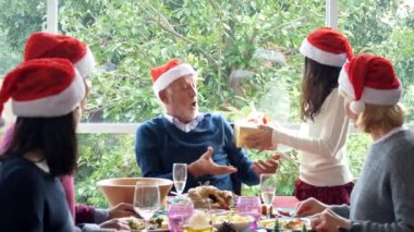 Mutlu bir aile Noel partisinde eğleniyor ve evde hediye kutuları veriyor.