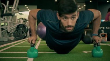 Genç adam spor salonunda şınav çekiyor.