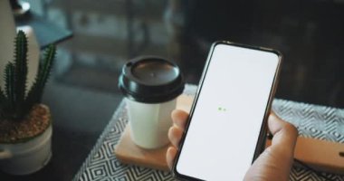 Müşteri kahve dükkanında sıcak içecek almak için e-ödemeyi cep telefonuyla yapıyor.