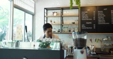 Barista kahvecide kahve servisi yapıyor ve gülümsüyor..